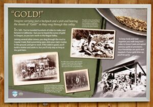 An informative sign with the title "Gold!" and multiple old photos collaged throughout. The first line reads "Imagine carrying just a backpack and a pick and hearing the shouts of "Gold!" as they rang through this valley."