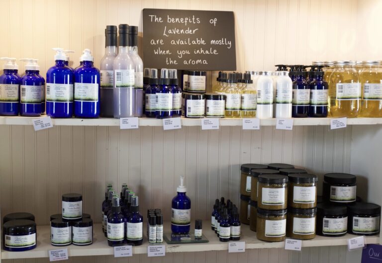 Two shelves against a white wall of tonics, soaps, and lotions in extravagant bottles. There is a sign that reads "the benefits of lavender are available mostly when you inhale the aroma."