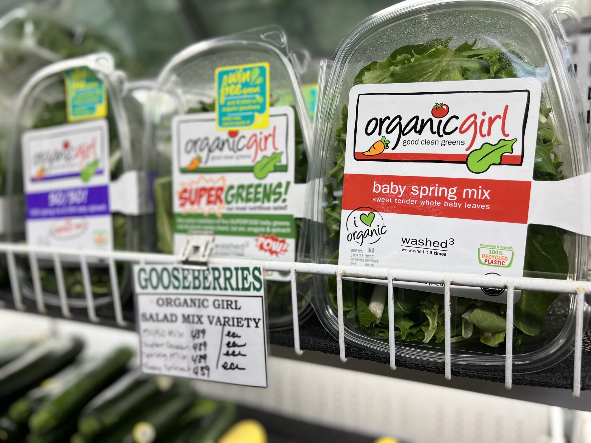 Shelf of packaged greens at Goosberries Market, the packaging reads "Organic Girl, Good Clean Greens."
