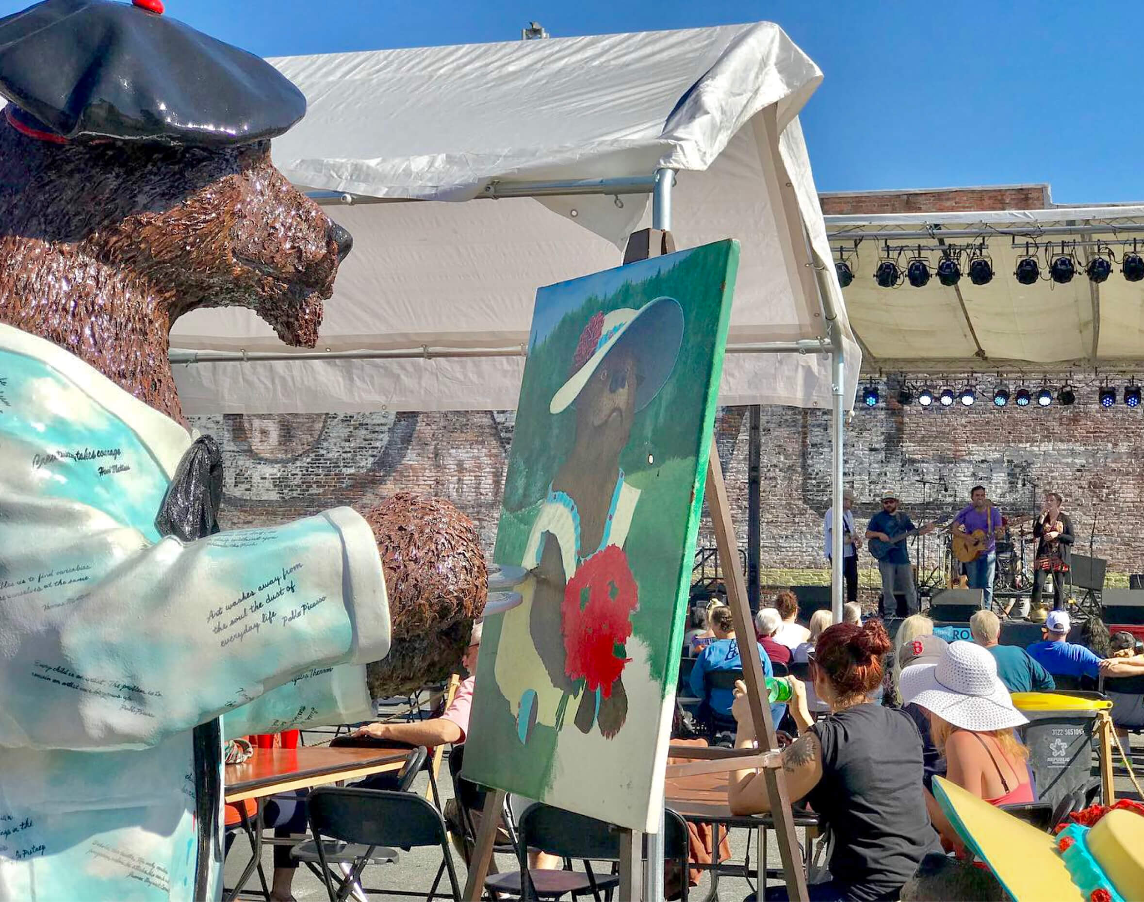 Grants Pass Bear Statue wearing a french berret, painting another bear in front of a concert.