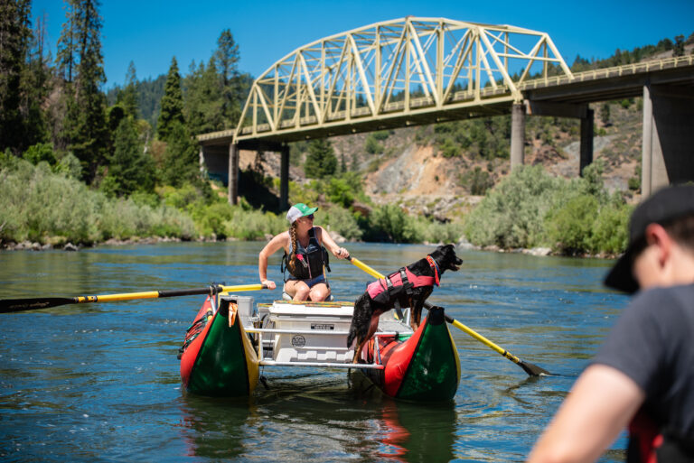 Passing under one of the many bridges in Grants Pass, a person and their dog drift on a pontoon down the Rogue River.