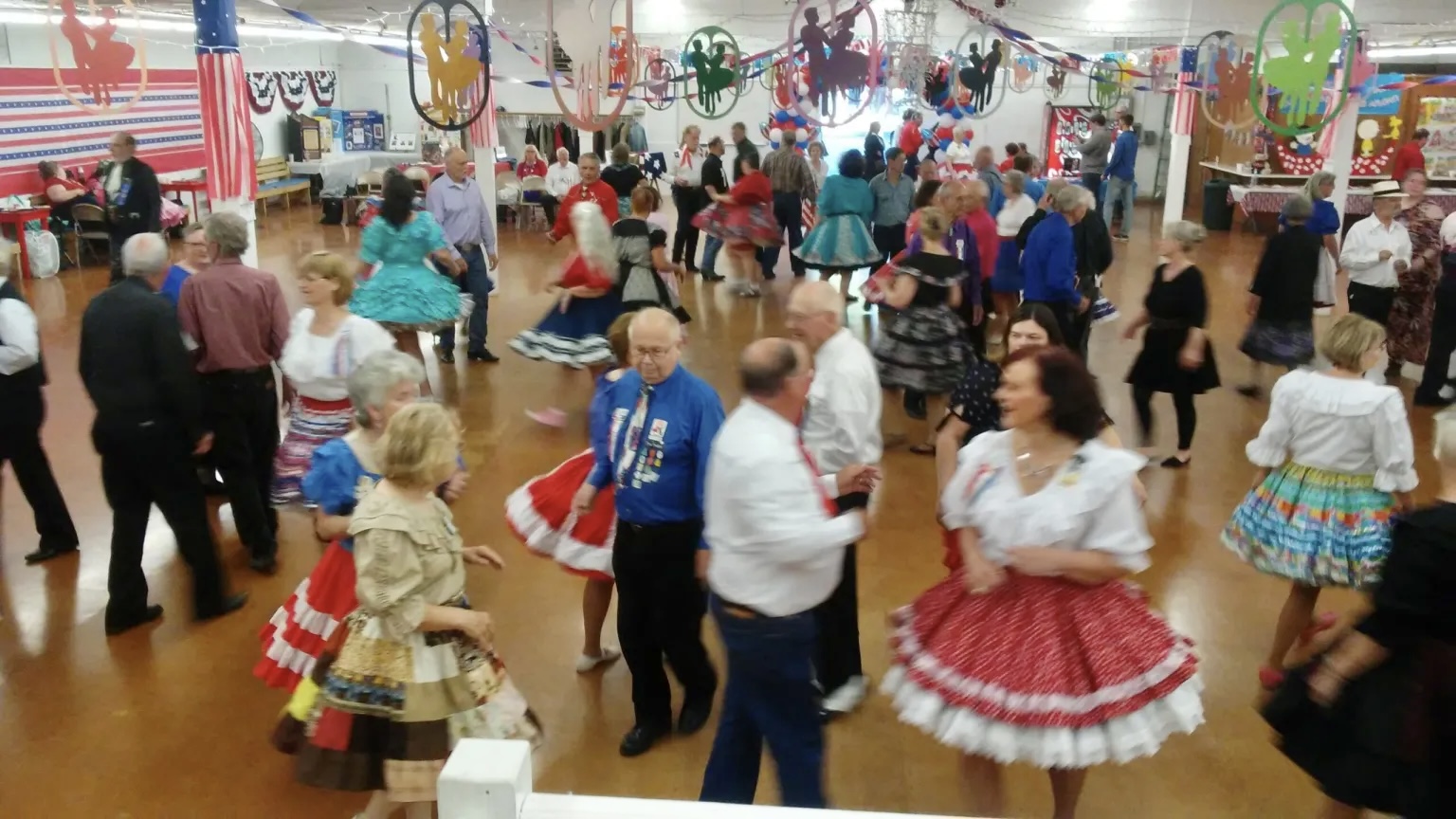 There is a packed room of dancers wearing old fashioned apparel and mingling at the 2022 Square Dance Festival, hosted at the Josephine County Fairgrounds.