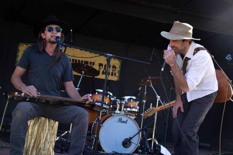 Brother, two singers each with a guitar and fedoras on the county fair stage.