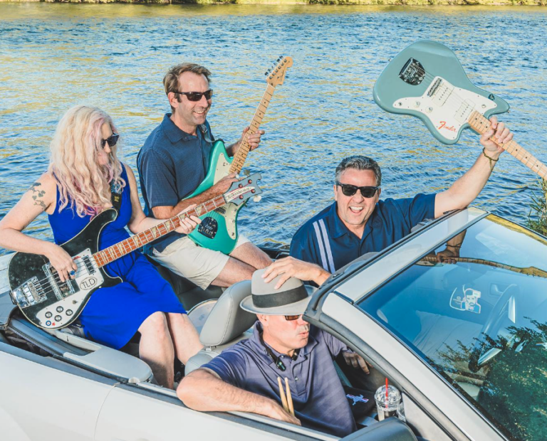 The Reverberays pulling up in a convertible car, all wearing sunglasses, three of them holding guitars, and one holding drum sticks.