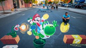 Art Along the Rogue chalk art of cartoon character with the artist.