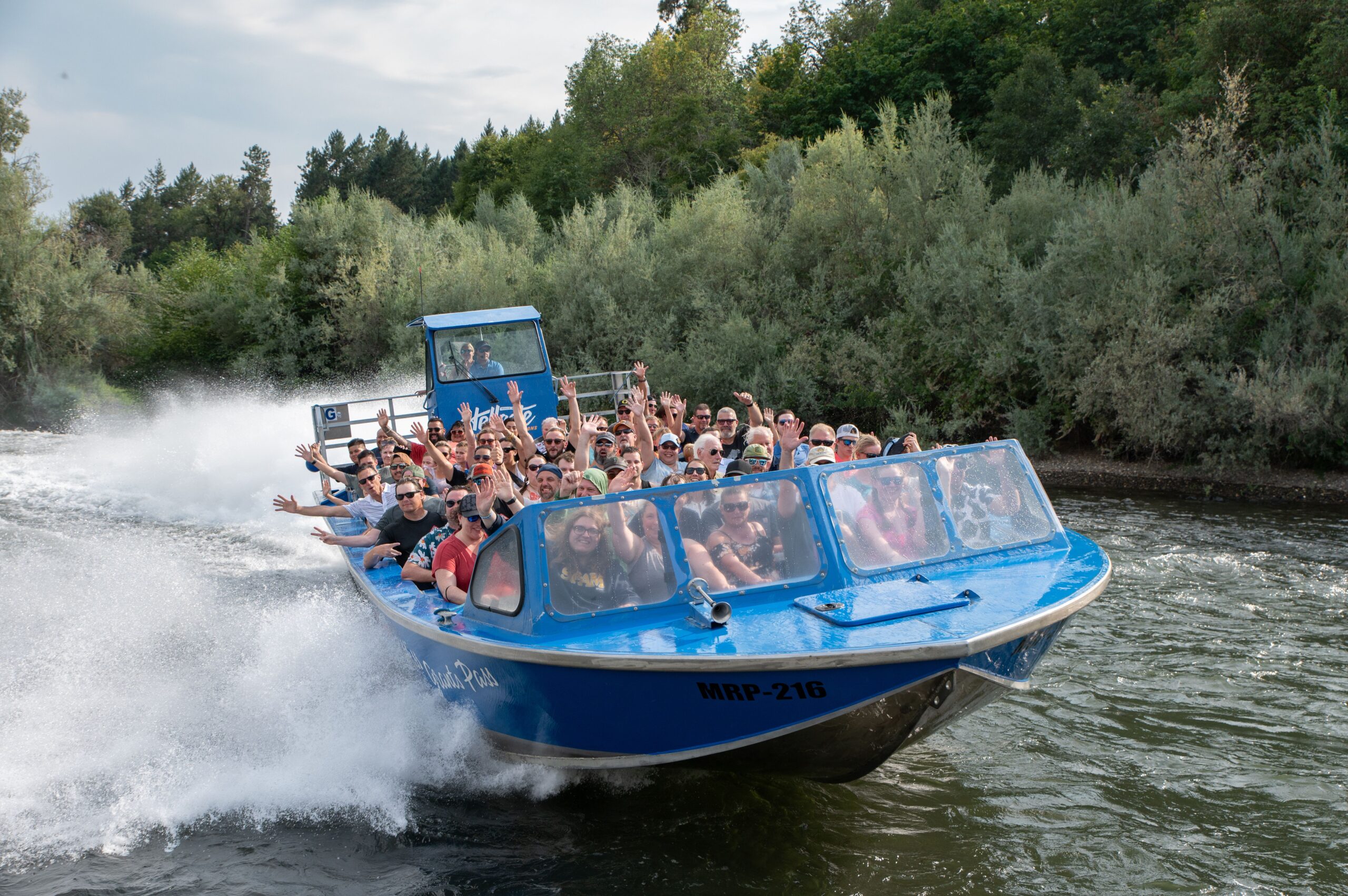 Crowd waves at the camera as the Hellgate Jetboat drifts on the Rogue River