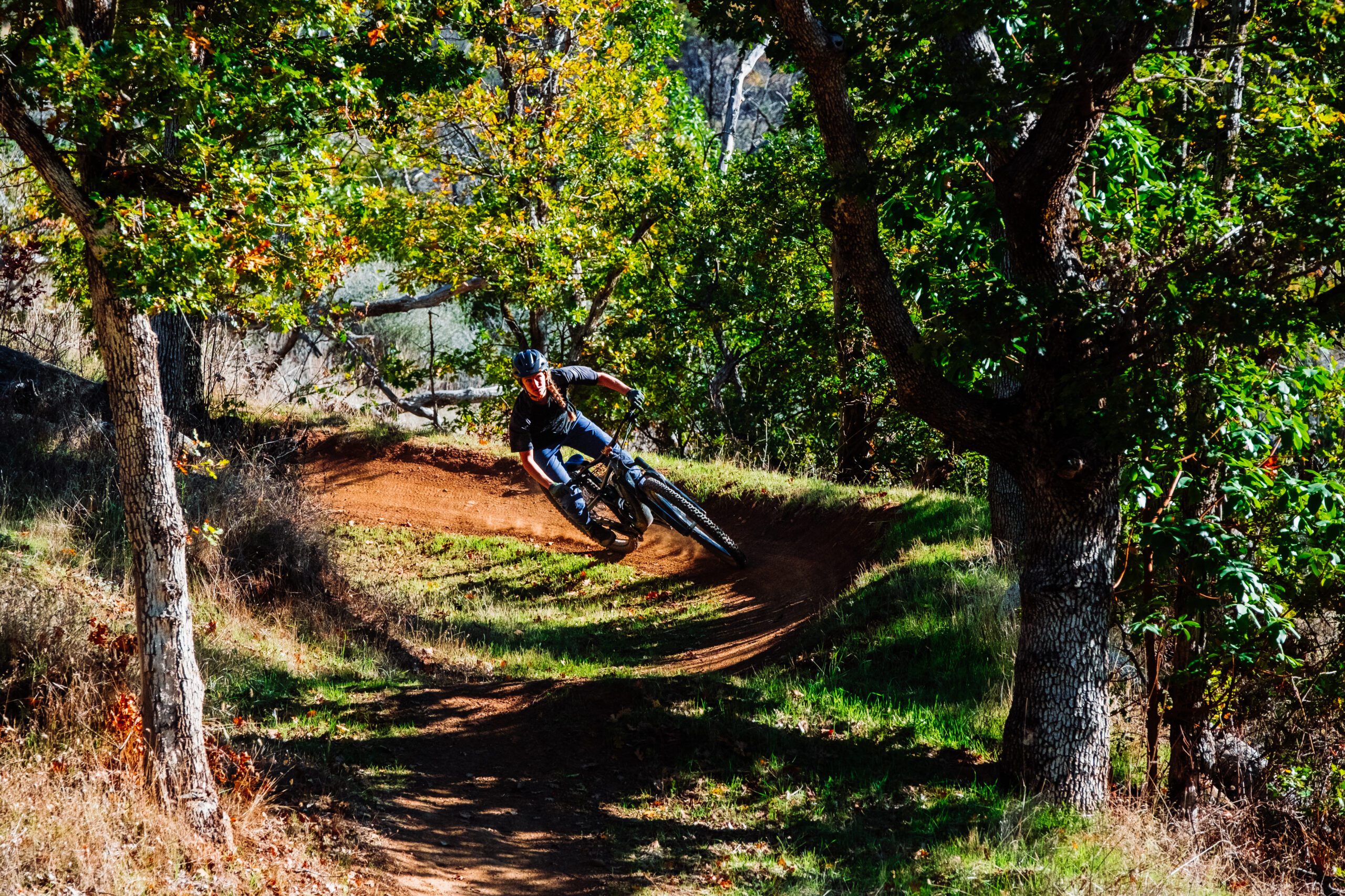 Mountain biker coming around a wide turn going down a bendy path.