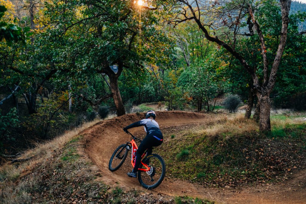 Mountain biker coming around a wide turn going down a bendy path.