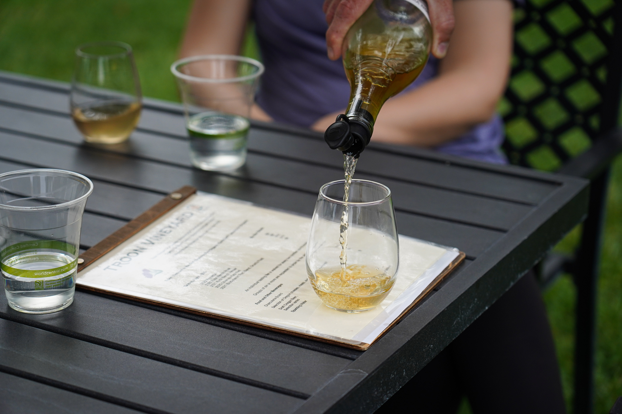 Pouring a glass of white wine at an outdoor table, located at Troon Vineyard.