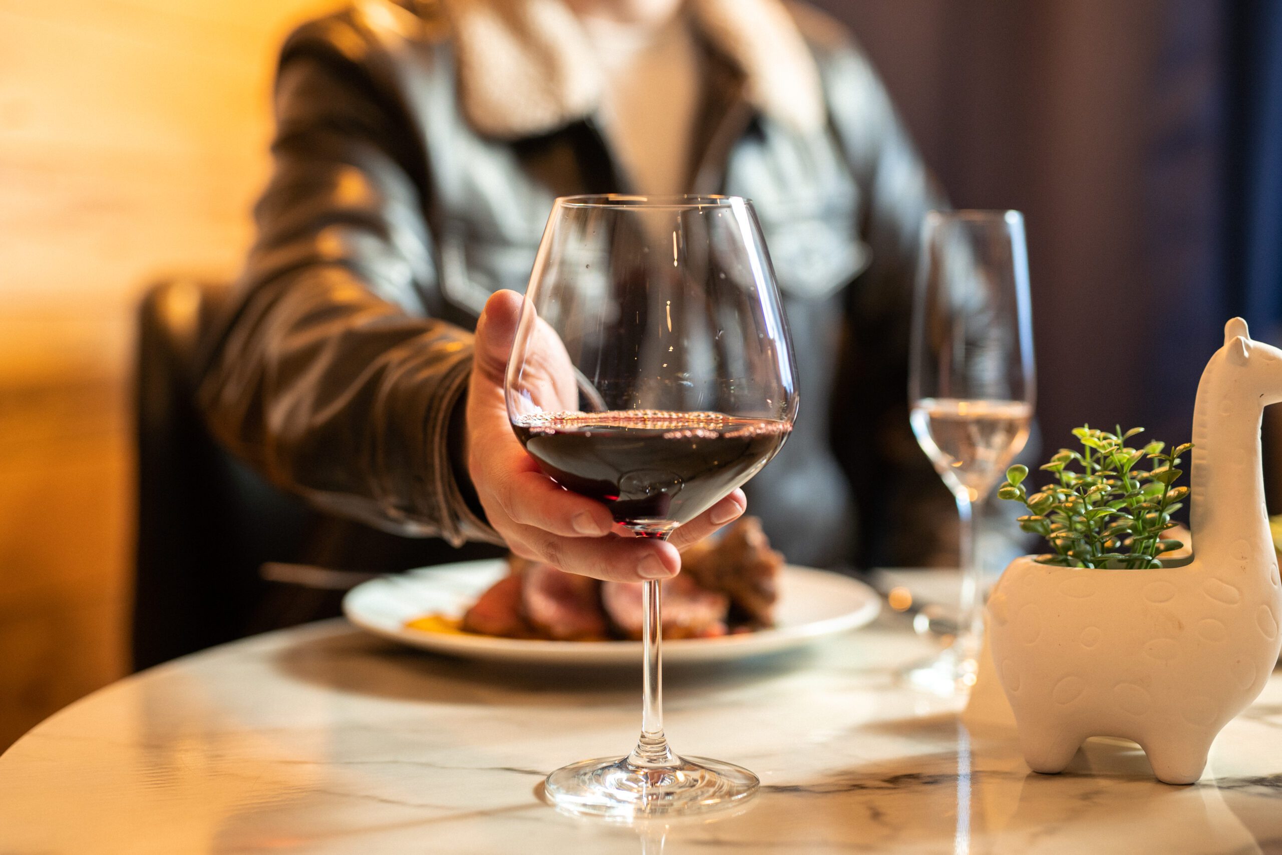 A glass of wine at Partake, Grants Pass. Ceramic giraffee with succulent on a marble table.